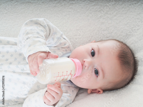 Baby boy drinking milk from the bottle at home