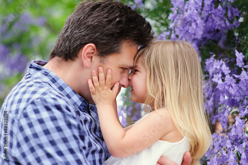 Young father and his cute daughter love in blooming garden