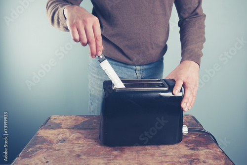 Young man sticking knife in toaster