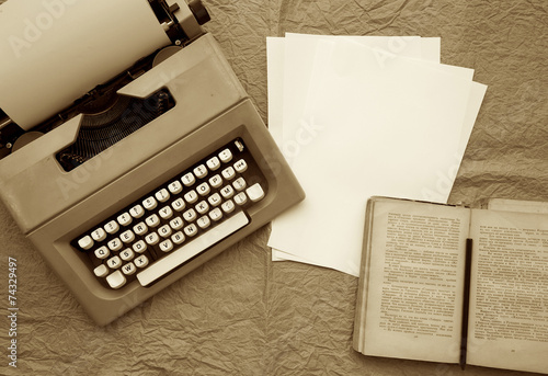 Typing machine, white sheets of paper,old book in Russian