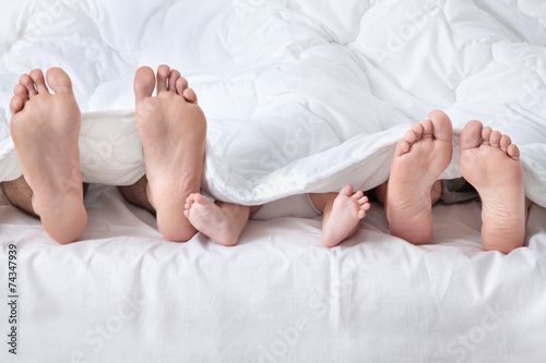 Feet of a family sticking out from the white quilt