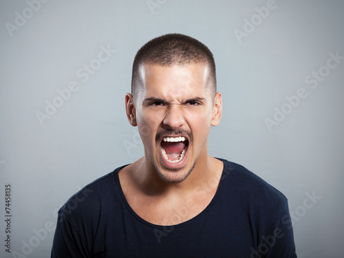 Portrait of a furious young man shouting. Studio shot.