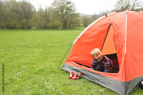 funny kid playing in a tent on the nature