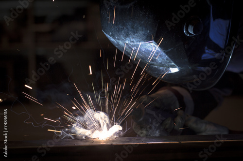 Employee welding steel using MIG/MAG welder.