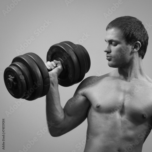 Handsome muscular male model with dumbbell. Black and white.