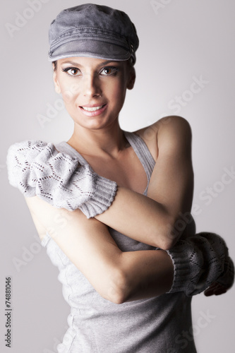 Beautiful woman with cap and gloves, on gray background
