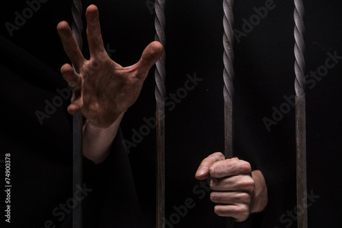 closeup on hands of man sitting in jail