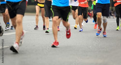 marathon athletes legs running on city road 