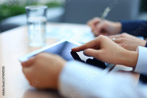 Image of two young businessmen using touchpad at meeting