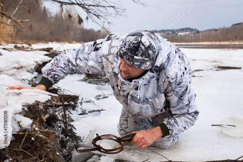 hunter putting a leghold trap for beaver
