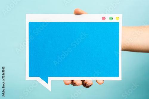 Hand holding blue computer software window, paper speech bubble.