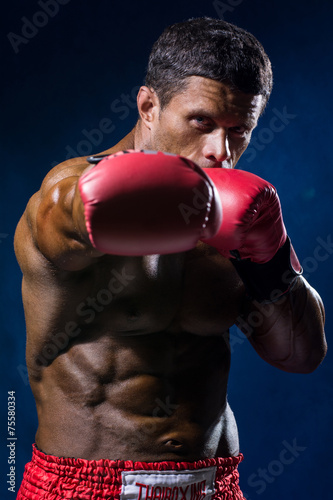 Strong muscular boxer in red boxing gloves.