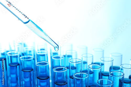 Pipette adding blue fluid to the one of test-tubes