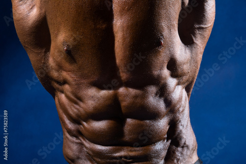 Close-up of abdominal muscles bodybuilder on a blue background