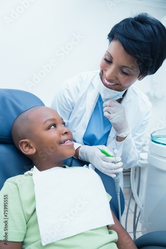 Smiling female dentist examining boys teeth