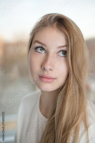 Charming teen girl is rolling her eyes up and looking