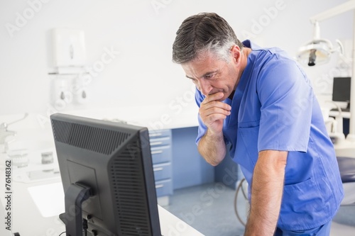 Thoughtful dentist using computer