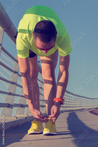 Tying the running shoes on a big bridge.