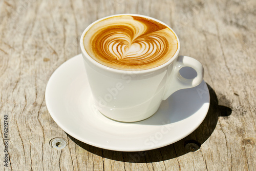 Cappuchino or latte coffe in a white cup with heart shaped foam