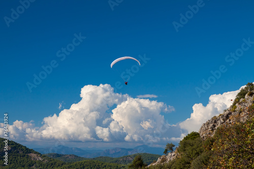 Paraglider flying over sky in summer day