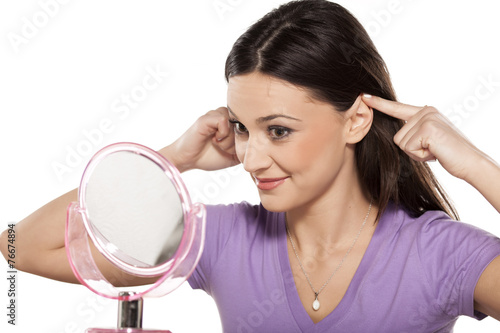 smiling girl touching her ears with the fingers in the mirror