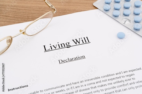 living will with pills and eyeglasses on wooden table