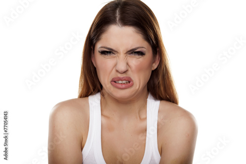 disgusted and frowning young woman on a white background