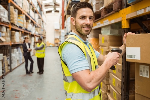 Warehouse worker scanning box while smiling at camera