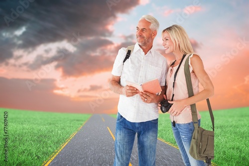 Composite image of happy tourist couple using the guidebook
