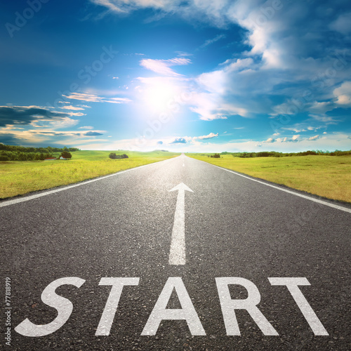 Empty asphalt road with a sign start against sun