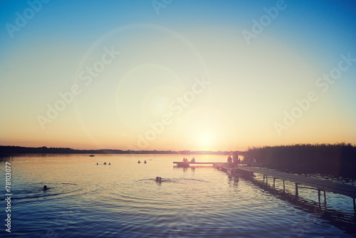 kąpielisko na jeziorze podczas zachodu słońca z flarą