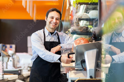 Shopkeeper cutting ham in a grocery store