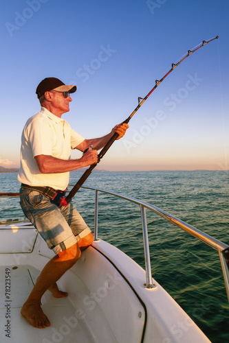 Angler fisherman fighting big fish on the ocean from the boat