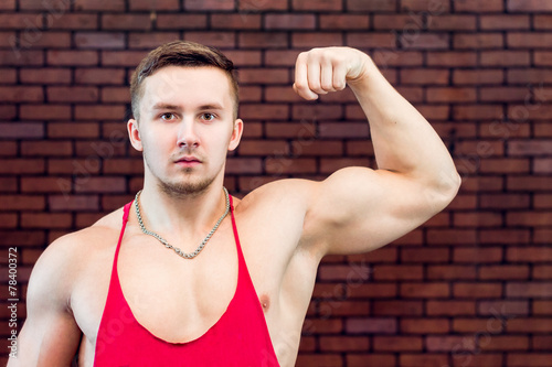 Beautiful , young athlete shows his inflated biceps.