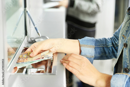 Female hand with money in cash department window. Currency
