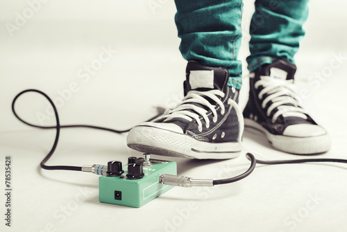 Rock player in sneakers stomp guitar overdrive pedal