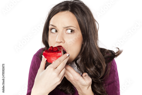 beautiful young woman eating cake secretly