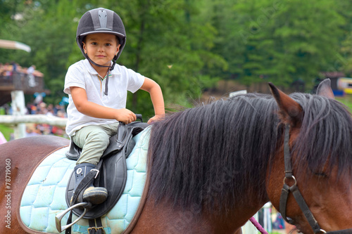 Child learns to ride a horse in a riding school