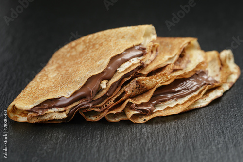 thin crepes or blinis with chocolate cream on slate board