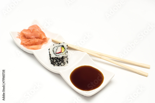 maki sushi with pickled ginger and soy sauce on white ceramic plate and chopsticks on white background