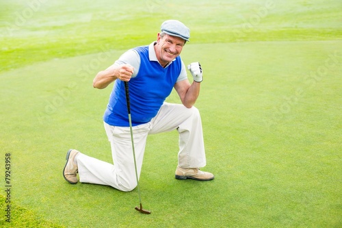 Smiling golfer kneeling on the putting green