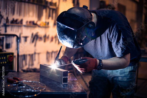 Employee welding aluminum using TIG welder in workshop.