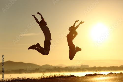 Fitness couple jumping happy at sunset