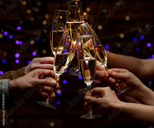Clinking glasses of champagne in hands on lights background