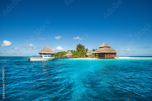 small tropical island with Beach Villas and speed boat