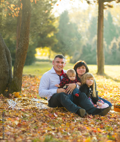 happy european family sitting on grass in the autumn park
