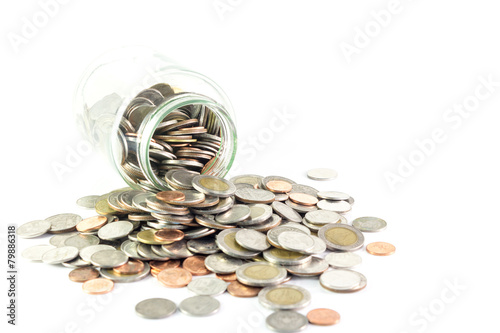 Isolated coins spilling from a money jar