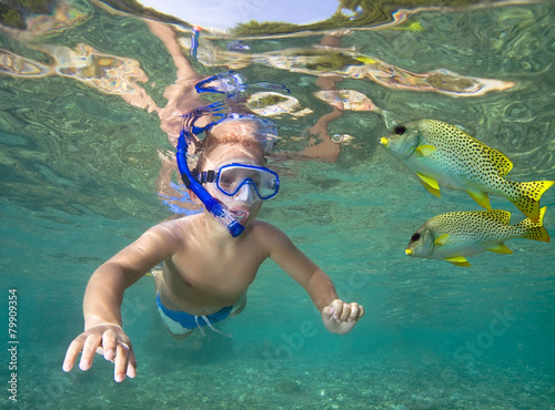 Small boy snorkeling with fish in a sea