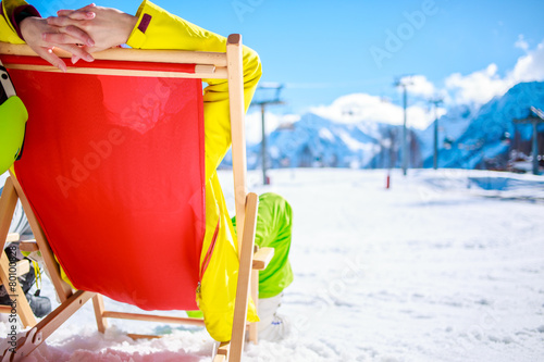 Women at mountains in winter lies on sun-lounger