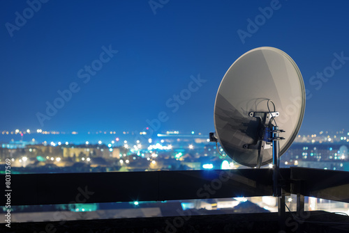 Satellite dish antenna on rooftop at night